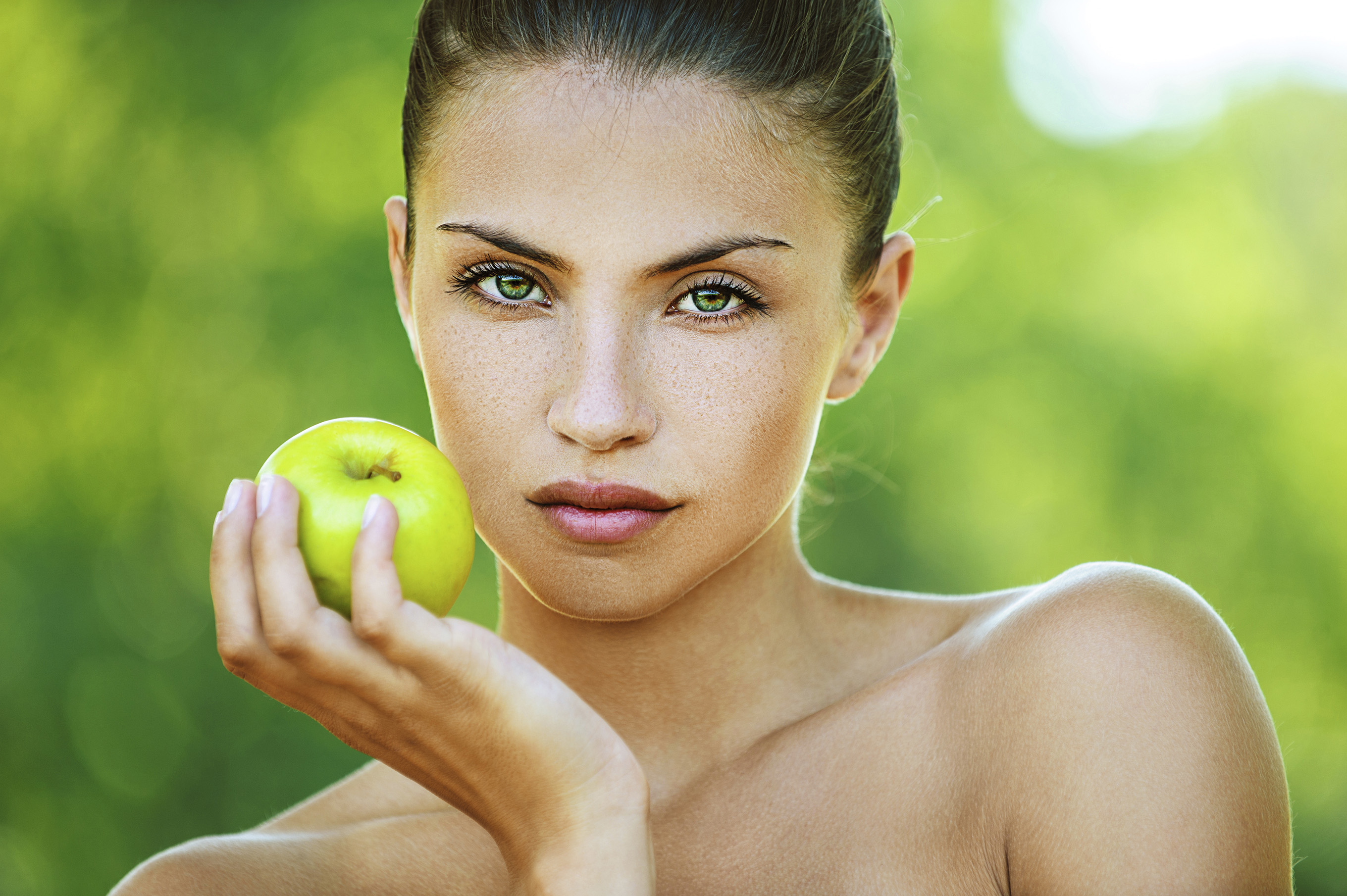 woman with bare shoulders holding an apple